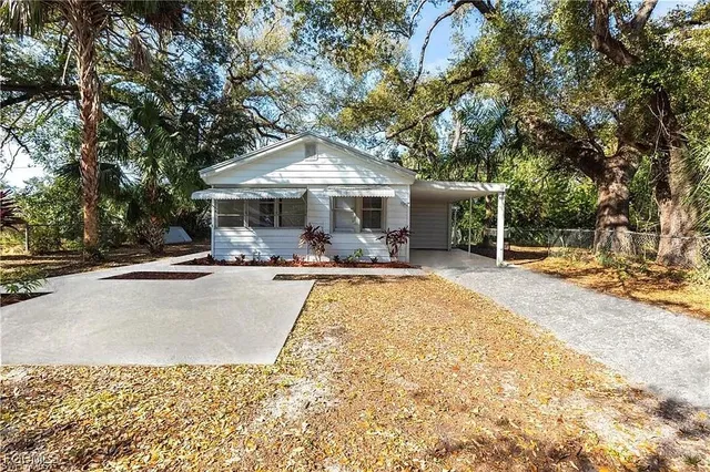 a view of a patio with couches and table and chairs under an umbrella with large trees