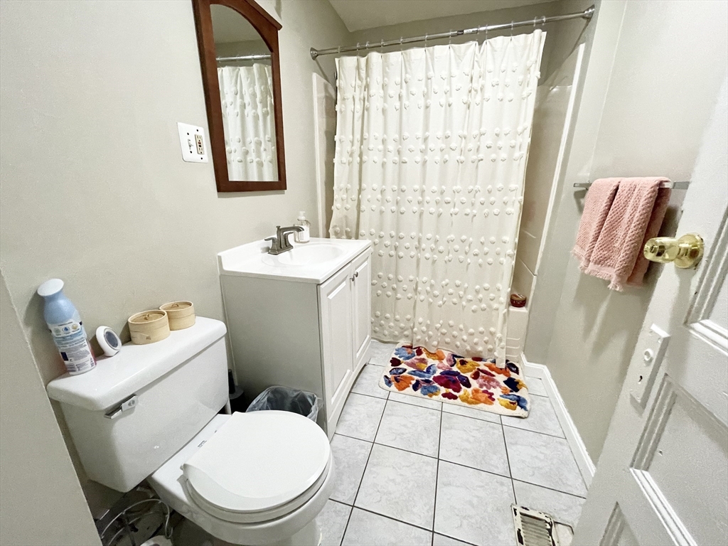 9 Taft Street, Unit 1 Boston, MA 02125 - Photo 15 of 15 a white toilet sitting next to a bathroom sink and a shower curtain