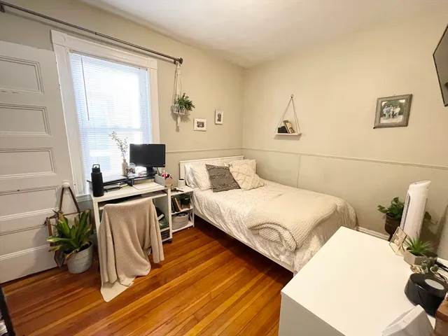 a bedroom with a bed and a computer on the desk next to a window