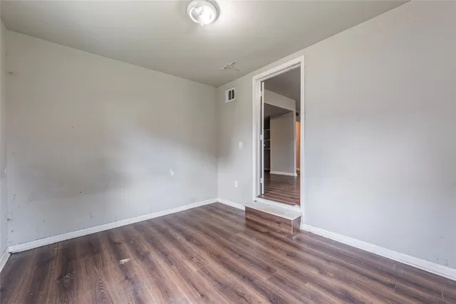an empty room with wooden floor chandelier fan and windows