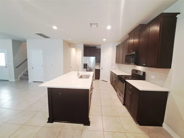 a large kitchen with a large counter top space and stainless steel appliances