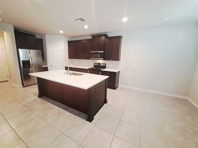 a large kitchen with a sink a counter top space stainless steel appliances and a counter top space
