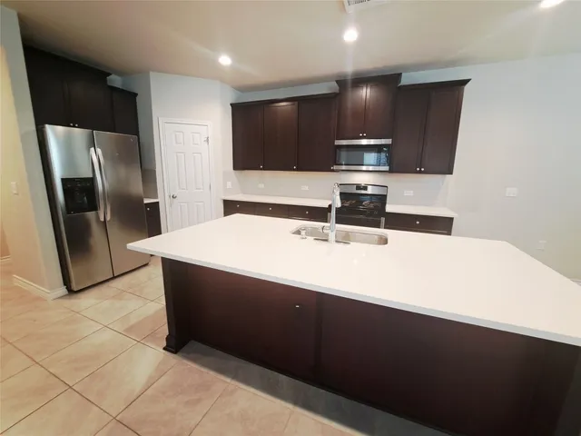 a kitchen with stainless steel appliances a sink a microwave a refrigerator and cabinets