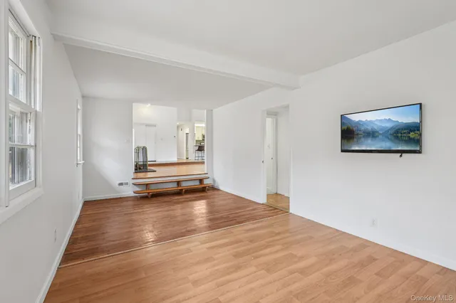 a view of empty room with wooden floor and window