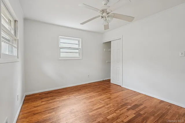 a view of a room with wooden floor and a ceiling fan