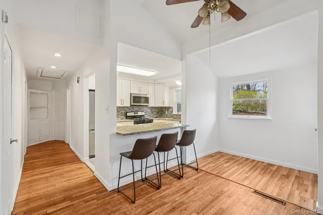 a living room with stainless steel appliances kitchen island granite countertop furniture and a wooden floor
