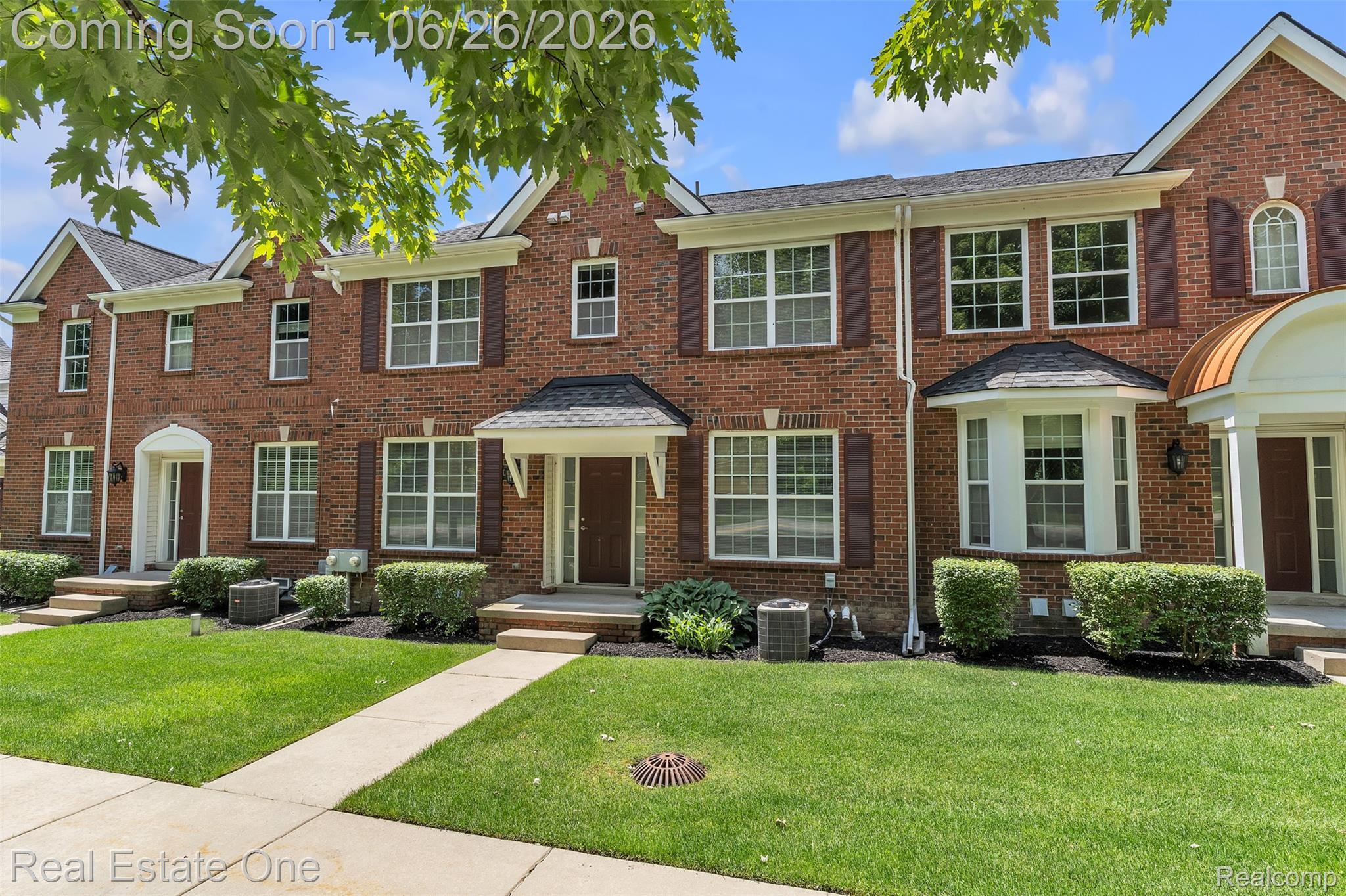 41590 Mitchell Road Novi, MI 48377 - Photo 5 of 45 Brick townhouse exterior featuring multiple white-trimmed windows with brown shutters, a gabled roofline, and a covered entry