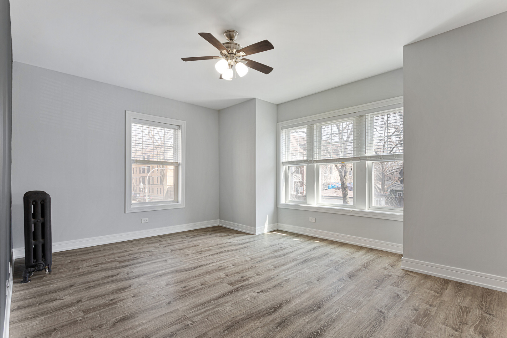 6942 North Wolcott Avenue, Unit 1 Chicago, IL 60626 - Photo 5 of 15 an empty room with wooden floor chandelier fan and windows