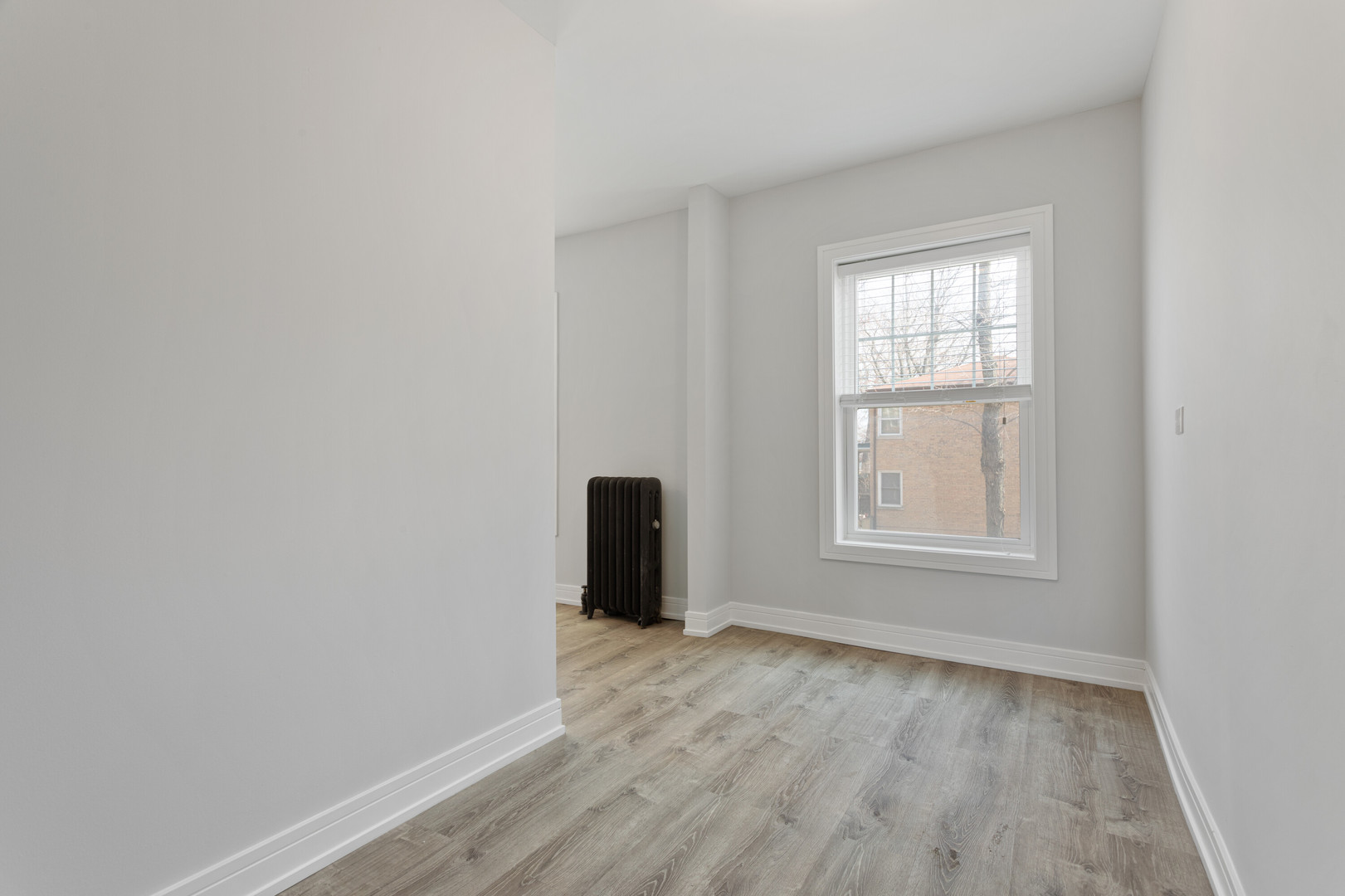 6942 North Wolcott Avenue, Unit 1 Chicago, IL 60626 - Photo 8 of 15 an empty room with wooden floor and windows