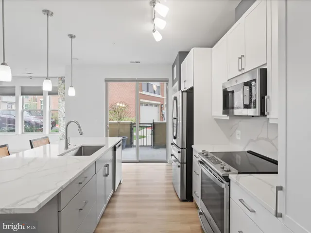 a kitchen with stainless steel appliances a table chairs refrigerator and cabinets