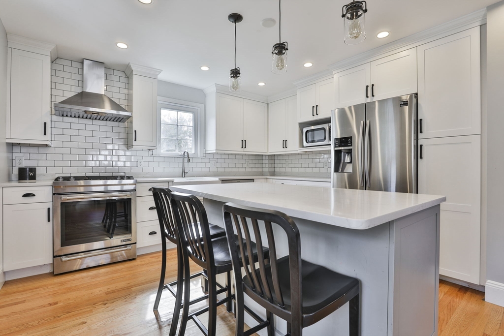 10 Lawndale Road Milton, MA 02186 - Photo 5 of 42 a kitchen with granite countertop a stove a sink a kitchen island with stainless steel appliances cabinets and wooden floor