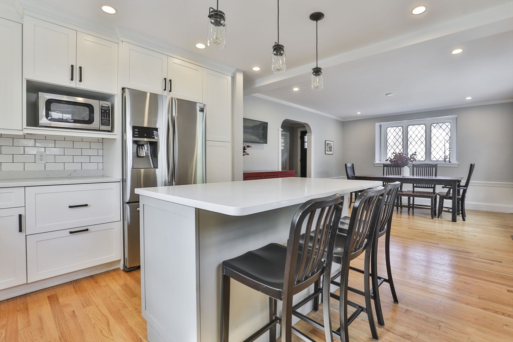 10 Lawndale Road Milton, MA 02186 - Photo 8 of 42 a kitchen with stainless steel appliances kitchen island granite countertop a dining table chairs refrigerator and sink