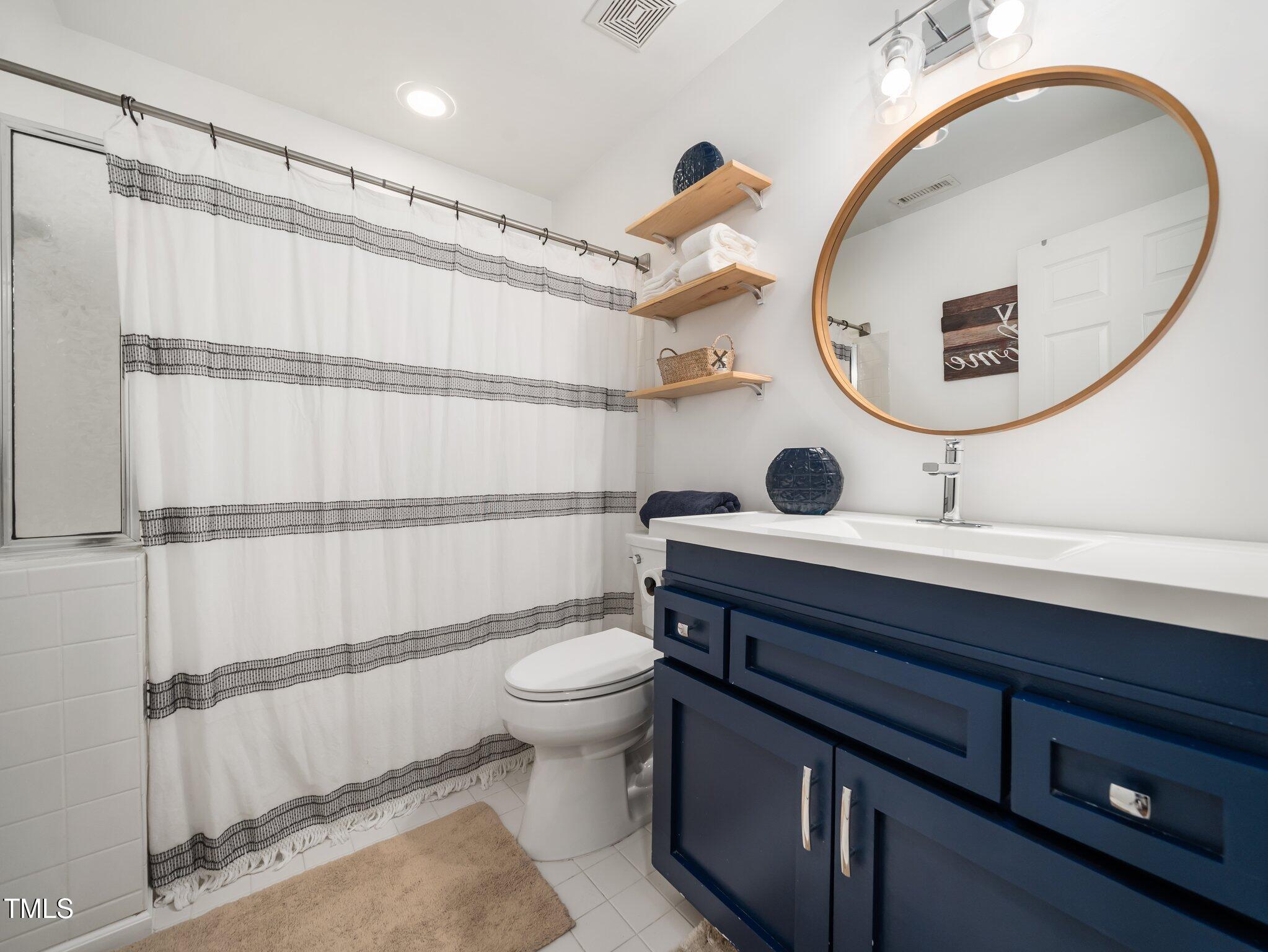 3400 Appling Way Durham, NC 27703 - Photo 22 of 30 a bathroom with a toilet a sink and mirror