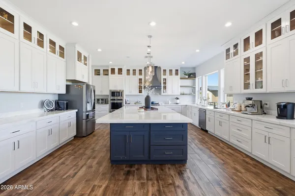 a large white kitchen with cabinets a sink a window and stainless steel appliances