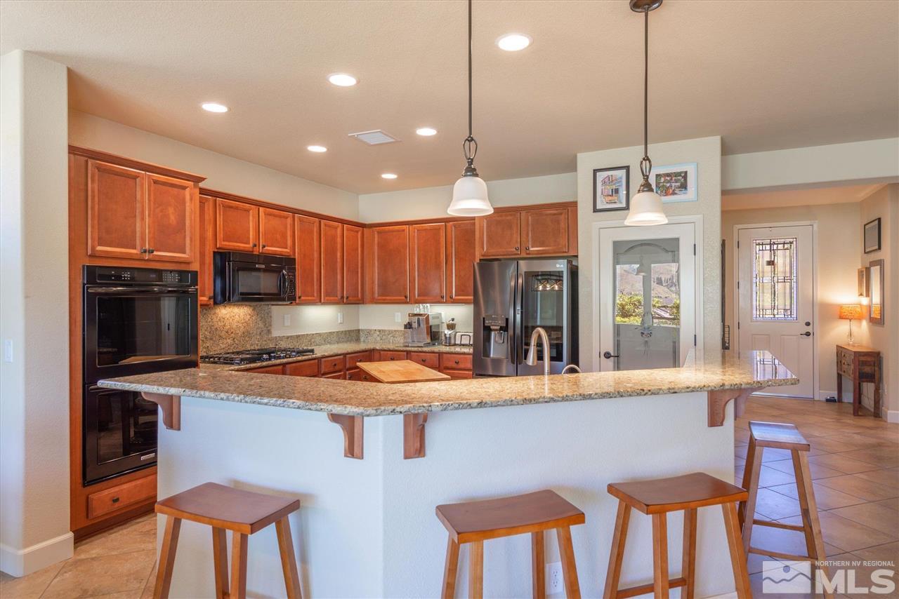 1149 Dutch Hollow Trail Reno, NV 89523 - Photo 8 of 38 a kitchen with stainless steel appliances granite countertop a stove a refrigerator a kitchen island a table and chairs