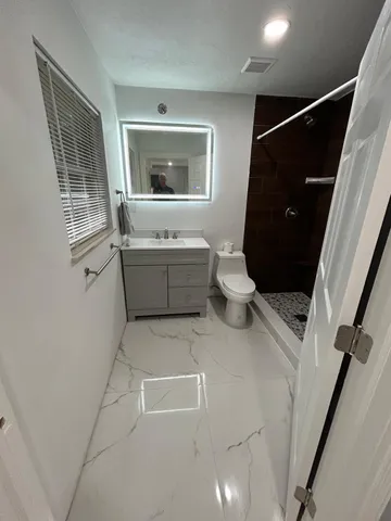 a bathroom with a sink a toilet and shower