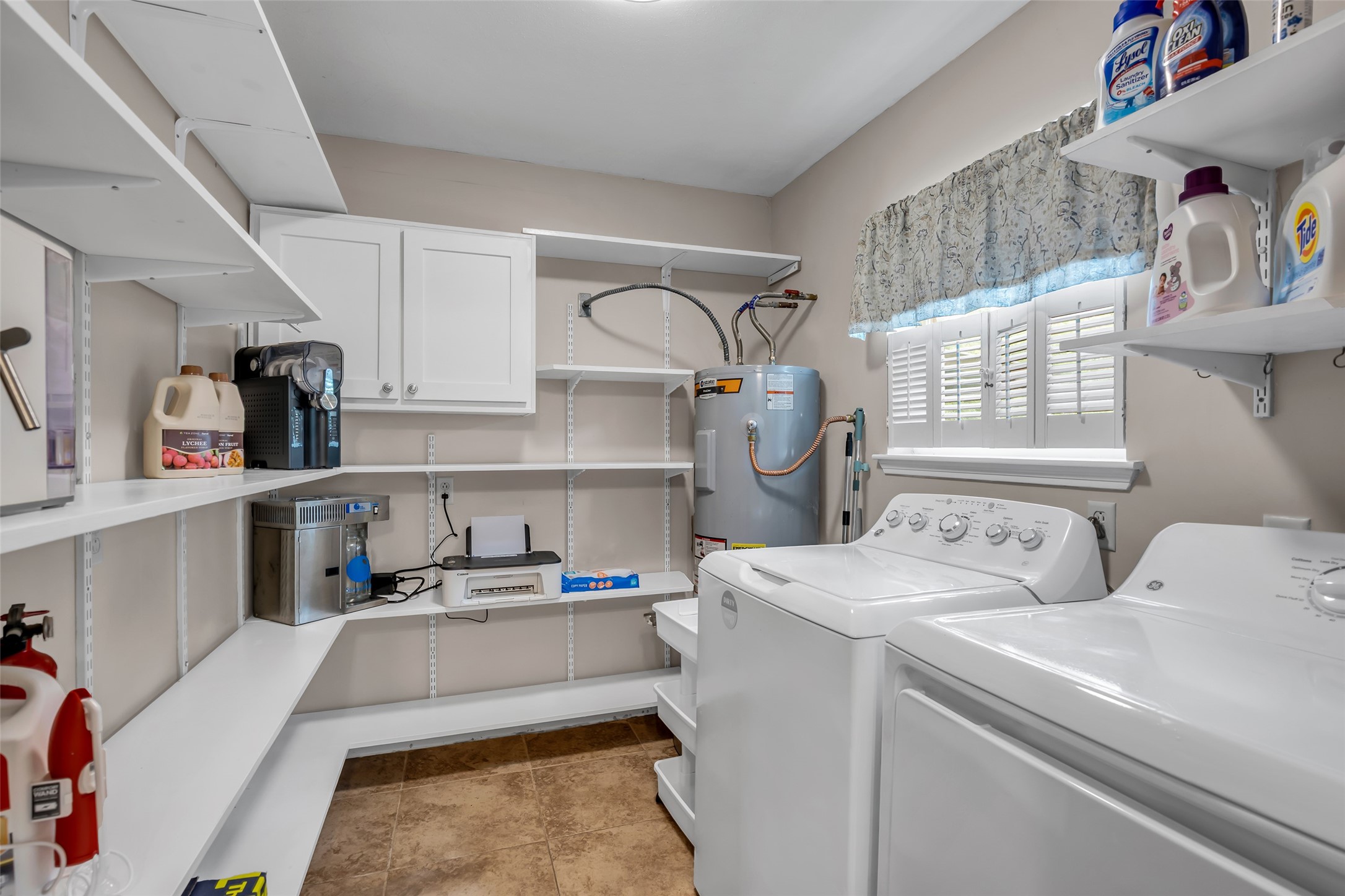 22502 Fields Lane Spring, TX 77389 - Photo 18 of 39 Spacious laundry room featuring a washer and dryer, ample shelving for storage, a water heater, and window. The space is neat and functional, offering convenience for household tasks.