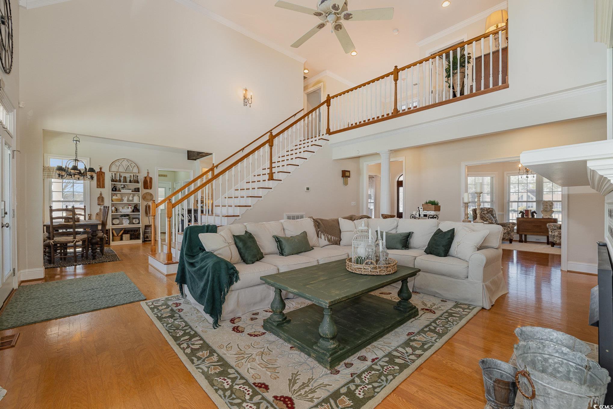 3658 Edwards Road Aynor, SC 29511 - Photo 8 of 39 Living room featuring hardwood / wood-style floors, a towering ceiling, ornamental molding, ceiling fan with notable chandelier, and ornate columns