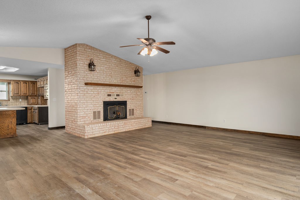  living room featuring a ceiling fan, lofted ceiling, dark wood-type flooring, and a fireplace
