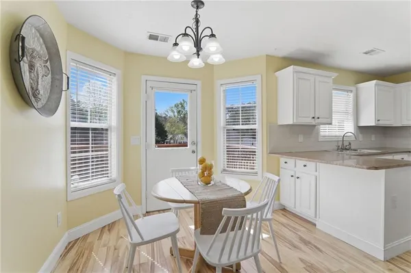 a kitchen with stainless steel appliances granite countertop a dining table chairs and a window