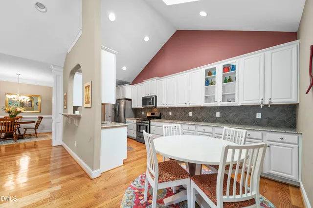 a kitchen with stainless steel appliances granite countertop a stove top oven a sink a dining table and chairs