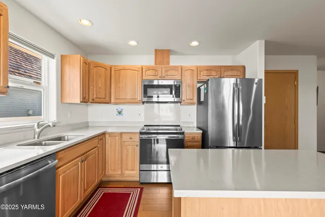 a kitchen with stainless steel appliances granite countertop a refrigerator a sink dishwasher a stove and a refrigerator