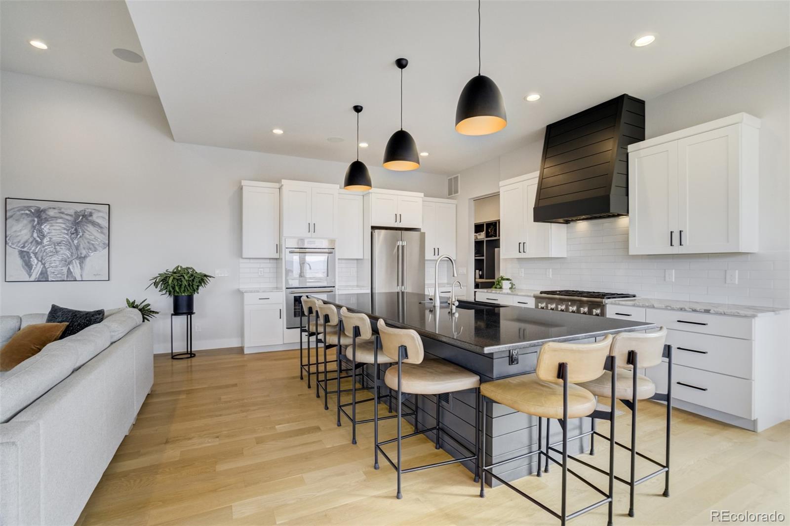 1287 Kelso Place Colorado Springs, CO 80921 - Photo 12 of 50 a kitchen with stainless steel appliances granite countertop a stove a sink a refrigerator and a dining table with wooden floor