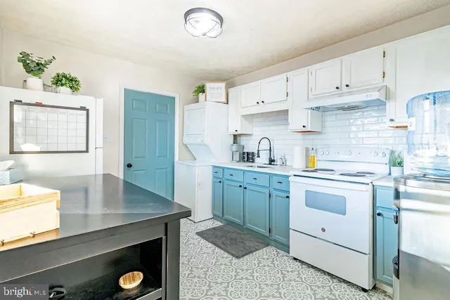 a kitchen with a sink dishwasher a stove and white cabinets with wooden floor