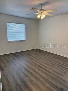 a view of an empty room with window and chandelier fan