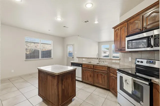 a large kitchen with a stove a refrigerator and a sink