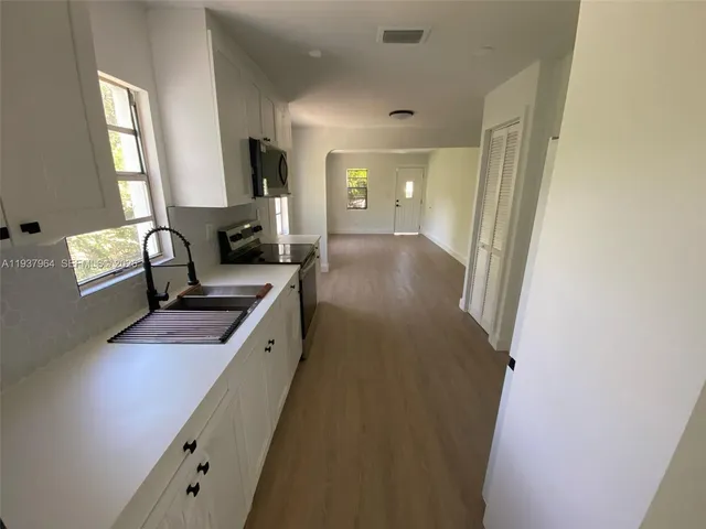a kitchen with granite countertop a sink stove and cabinets