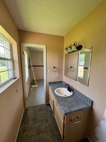 a spacious bathroom with a granite countertop sink and a mirror