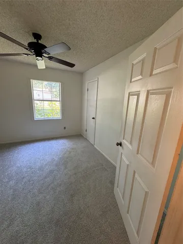 en empty room with windows and a ceiling fan