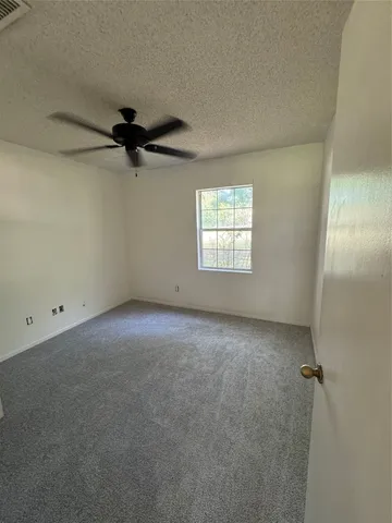 an empty room with a window and a fan