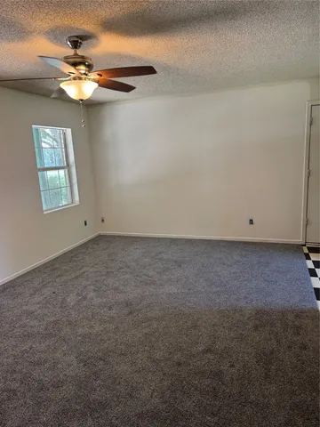 an empty room with a chandelier fan and windows