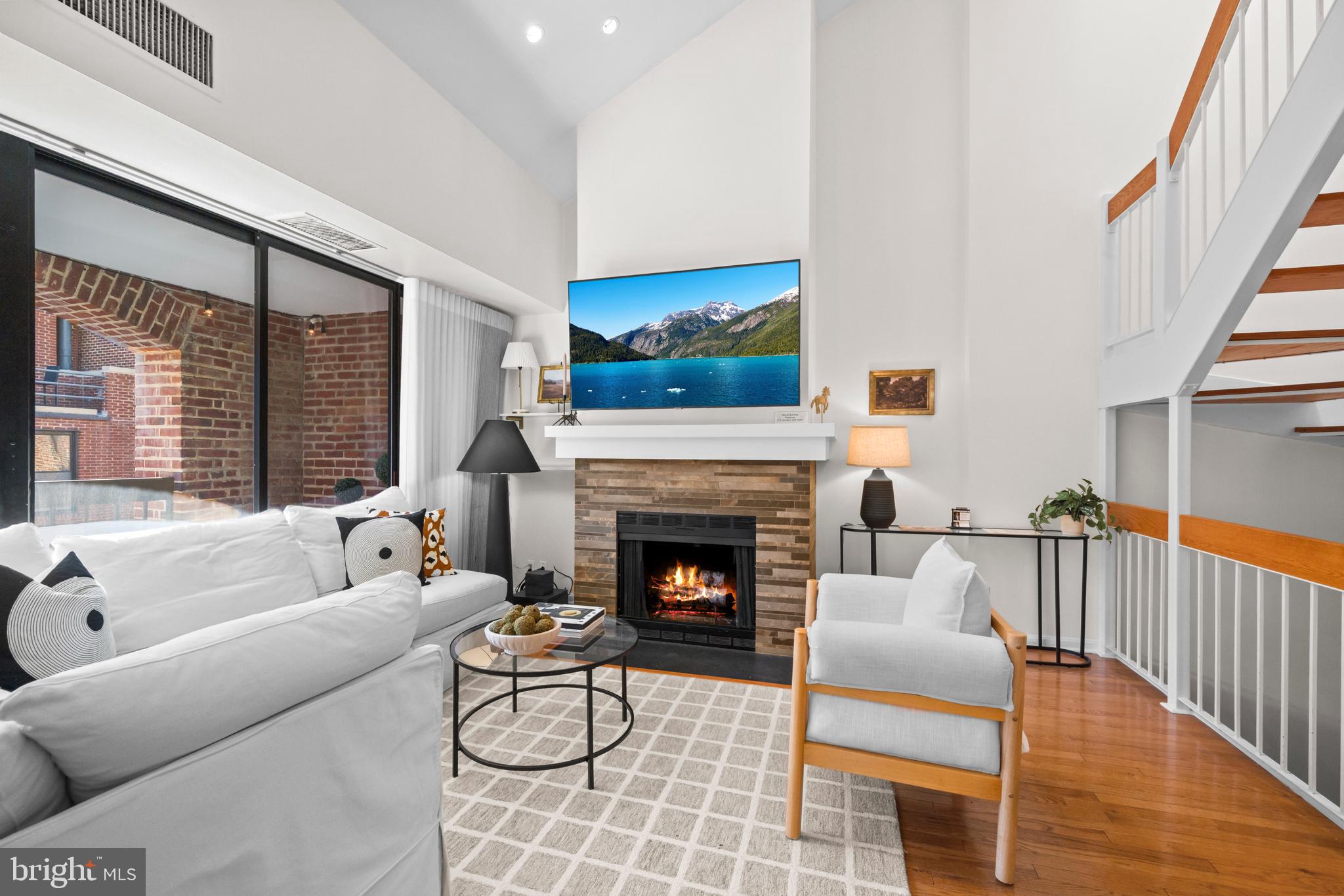 3225 Grace Street Northwest, Unit 219 Washington, DC 20007 - Photo 6 of 45 a living room with furniture a fireplace and a floor to ceiling window