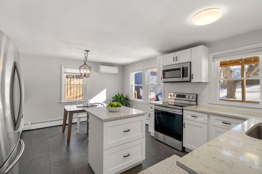356 Central Street Framingham, MA 01701 - Photo 6 of 25 a kitchen with stainless steel appliances kitchen island granite countertop a stove a sink dishwasher and a refrigerator with wooden floor