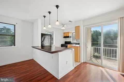 a kitchen with granite countertop a stove a sink a refrigerator and wooden floor