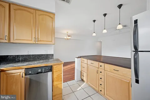 a kitchen with stainless steel appliances granite countertop a refrigerator a sink and white cabinets