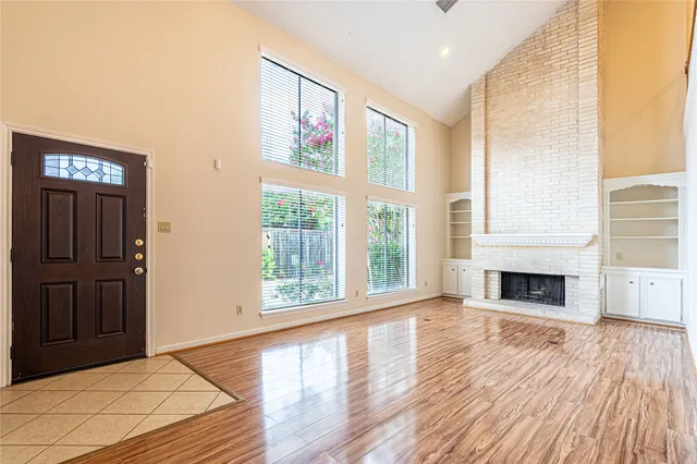 a view of a livingroom with wooden floor fireplace and windows