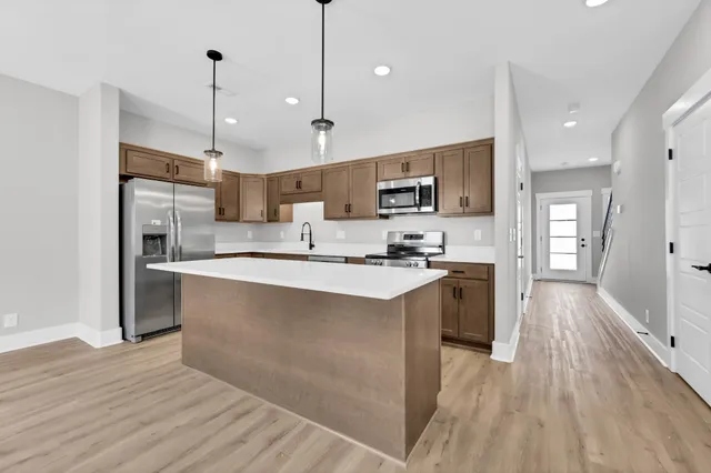 a kitchen with kitchen island a sink a stove a refrigerator and a wooden floor
