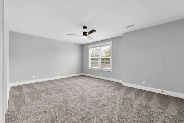 an empty room with windows and chandelier fan