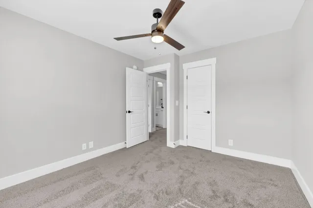 an empty room with a ceiling fan and carpet