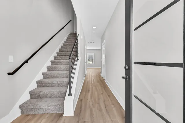 a view of staircase with wooden floor and white walls