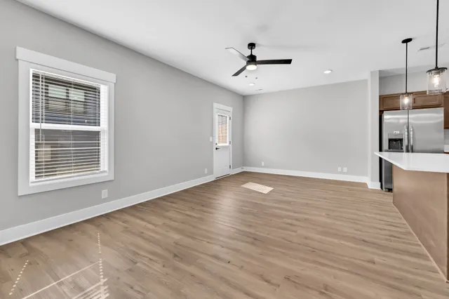 a view of an empty room with window and wooden floor