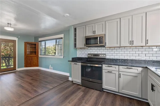 a kitchen with granite countertop a stove a sink and a microwave