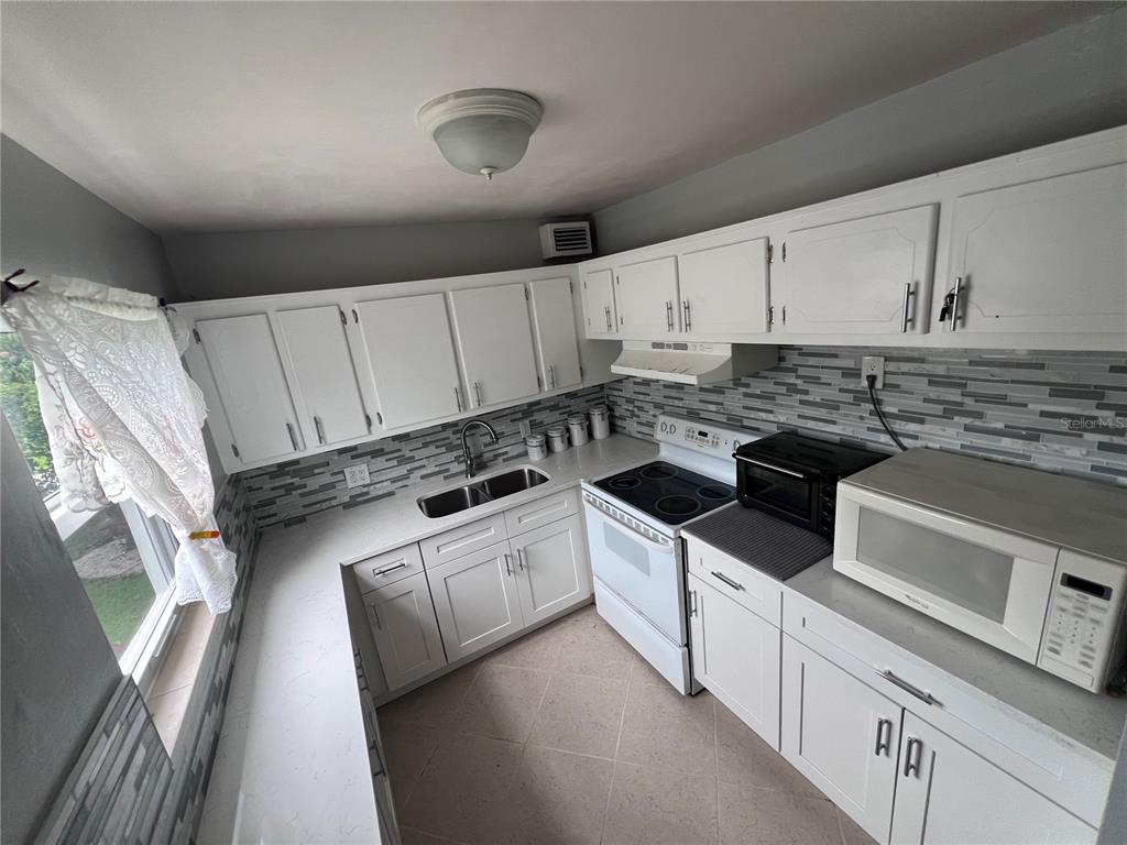 240 Northampton L, Unit 240 West Palm Beach, FL 33417 - Photo 7 of 11 a kitchen with stainless steel appliances granite countertop a stove and a sink