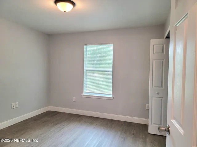 a view of a hallway with front door and wooden floor
