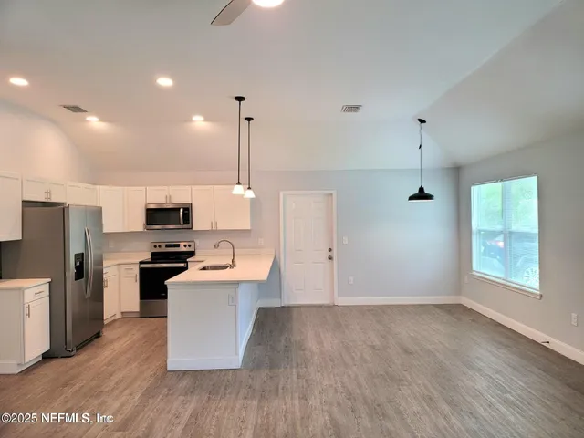 a kitchen with stainless steel appliances a stove top oven a refrigerator a sink and dishwasher with wooden floor