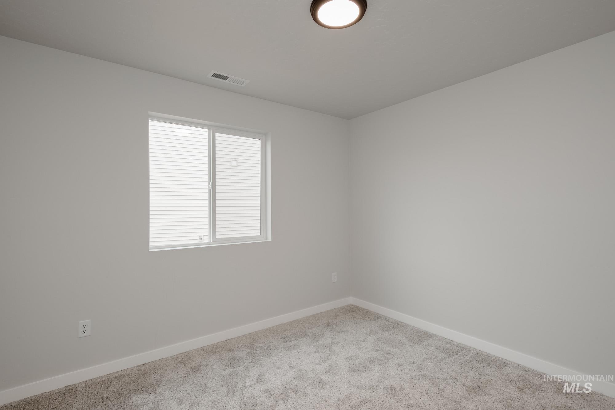 2391 West Fallon Loop Nampa, ID 83651 - Photo 10 of 20 Neutral-toned room featuring a single window with blinds, light gray walls, white baseboards, and textured gray carpeting